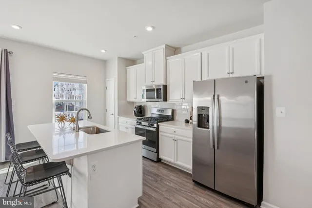 a kitchen with stainless steel appliances a refrigerator a stove a sink cabinets and a dining table