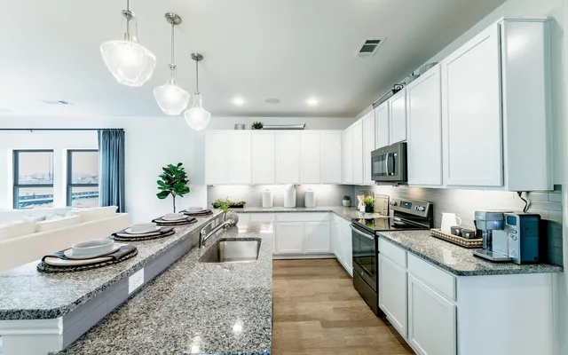 a large kitchen with stainless steel appliances granite countertop a lot of counter space and a sink
