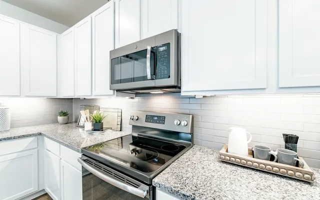 a kitchen with stainless steel appliances granite countertop a stove a microwave and a sink