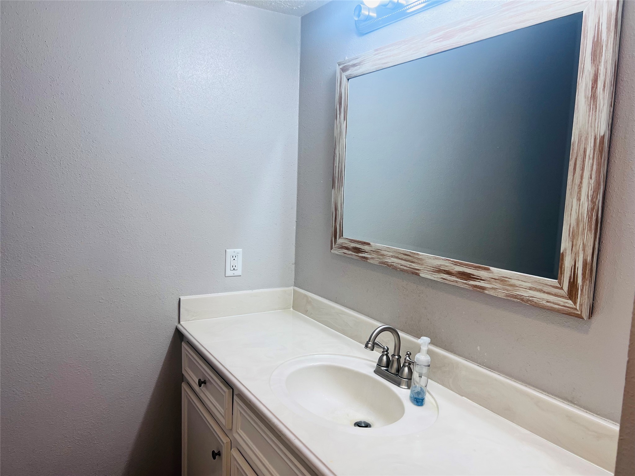 902 Hidden Canyon Road Katy, TX 77450 - Photo 14 of 20 Bathroom vanity with a single sink, featuring a modern faucet. Above it, there's a large mirror with a rustic wooden frame.