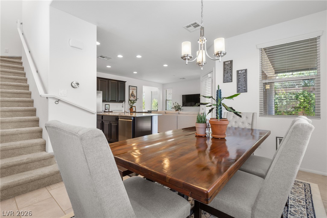 891 Earth Luster Road Las Vegas, NV 89178 - Photo 47 of 48 A lustrous wooden dining table with seating connects seamlessly to a modern kitchen and living space, offering an open floorplan.