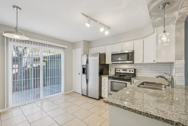 a kitchen with stainless steel appliances granite countertop a refrigerator a stove top oven a sink and dishwasher