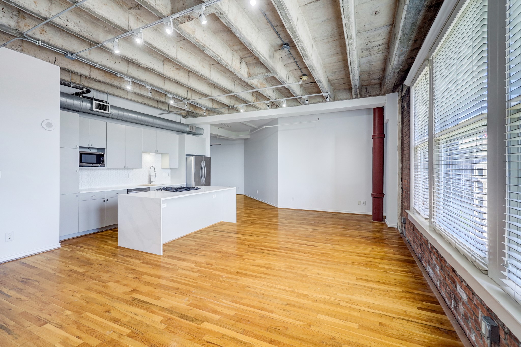 a room with stainless steel appliances wooden floors and large window