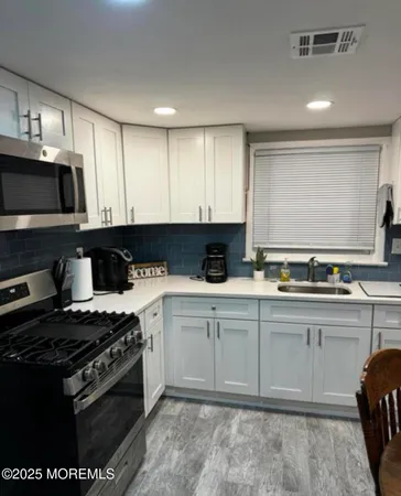 a kitchen with stainless steel appliances granite countertop a stove a sink and a microwave