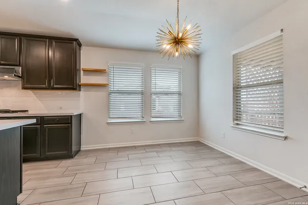 a view of an empty room with a kitchen and a window
