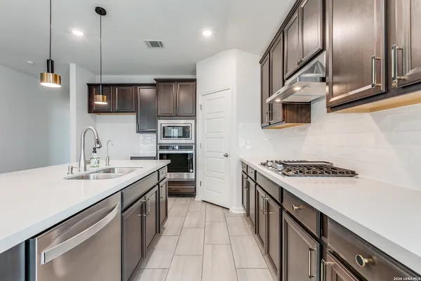 a kitchen with stainless steel appliances granite countertop a sink a stove top oven a counter space and cabinets