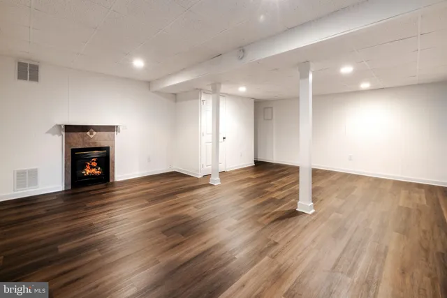 an empty room with wooden floor and a fireplace