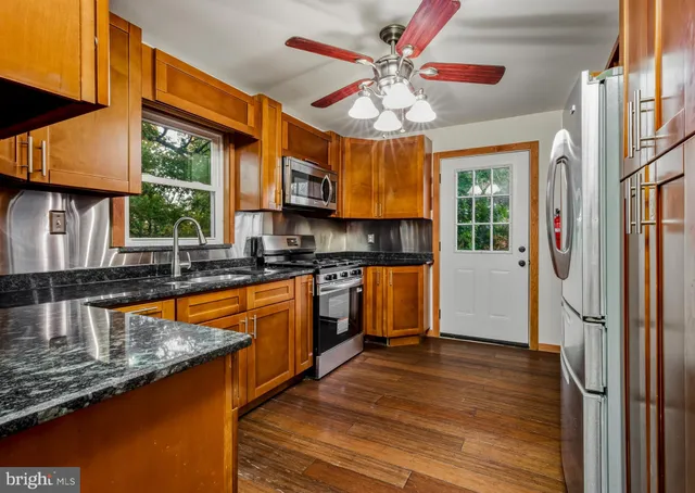a kitchen with stainless steel appliances granite countertop a sink a stove and a refrigerator