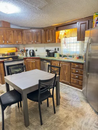 a kitchen with stainless steel appliances granite countertop a table chairs sink refrigerator and cabinets