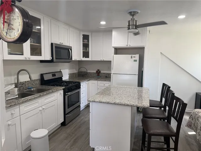 a kitchen with stainless steel appliances granite countertop a sink a stove a refrigerator cabinets and chairs