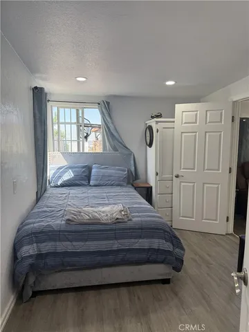 a spacious bedroom with a bed and wooden floor