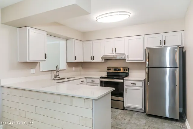a kitchen with a refrigerator sink and white cabinets