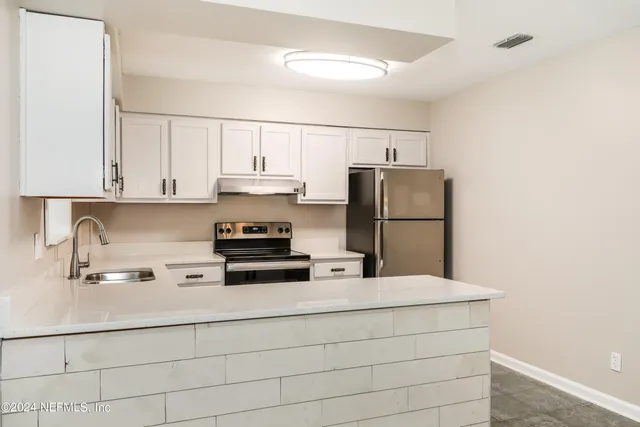 a kitchen with kitchen island a sink a refrigerator and cabinets