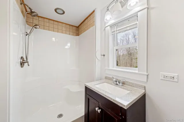 a bathroom with a granite countertop toilet a sink a mirror and a window