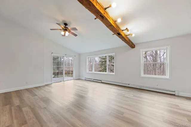 a view of an empty room with wooden floor and windows