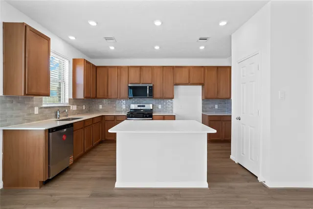 a large kitchen with stainless steel appliances granite countertop a stove a sink a refrigerator and a microwave