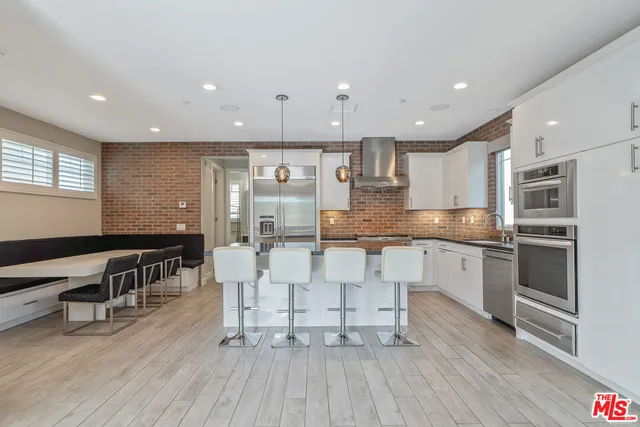 a kitchen with stainless steel appliances kitchen island granite countertop a stove top oven a sink a dining table and chairs