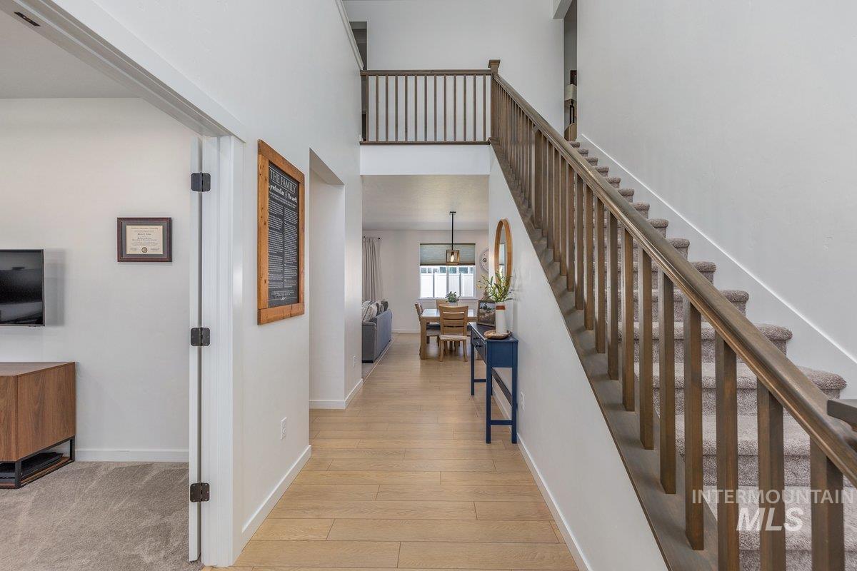 1380 West Chilitna Street Meridian, ID 83642 - Photo 4 of 50 Open-concept entryway featuring wood-finish flooring, a carpeted staircase with wood banister, and a second-story landing with wood railing