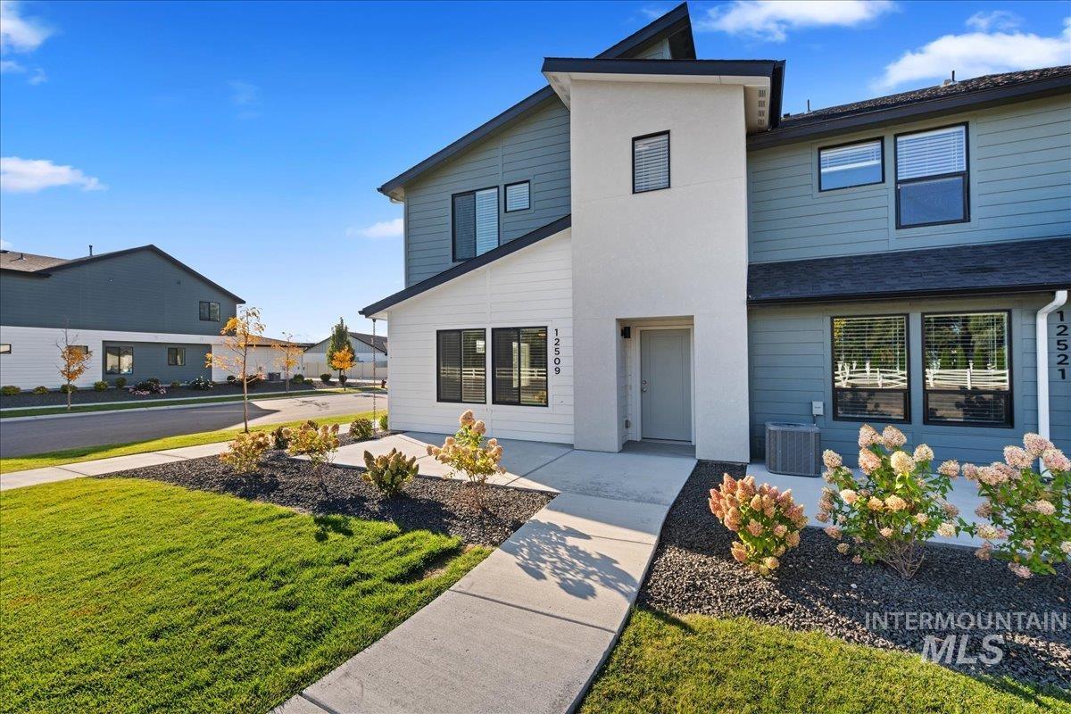 12509 West Victory Road Boise, ID 83709 - Photo 3 of 23 Modern exterior with a two-tone facade, prominent entry tower, black-framed windows, and manicured landscaping
