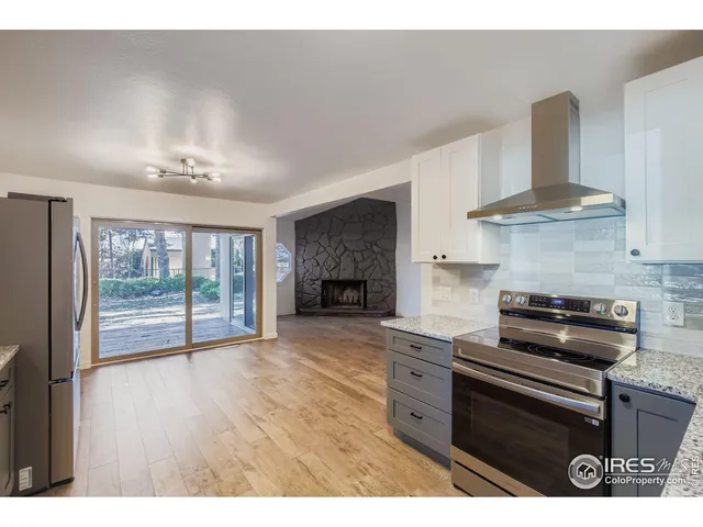 a kitchen with stainless steel appliances granite countertop a stove a refrigerator and a granite counter tops with wooden floors