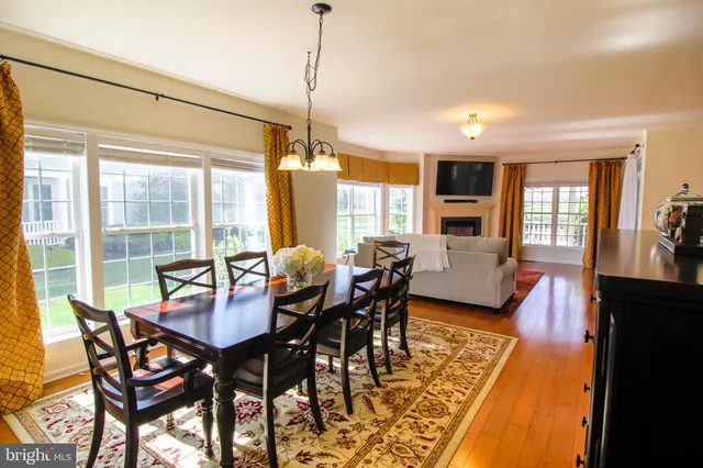 a kitchen with stainless steel appliances granite countertop a stove top oven a sink a dining table and chairs