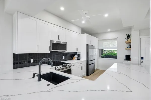 a kitchen with stainless steel appliances kitchen island granite countertop a sink a stove a refrigerator and cabinets