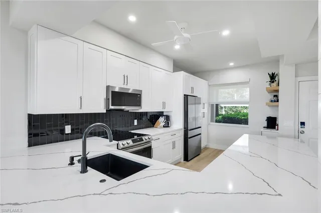 a kitchen with stainless steel appliances kitchen island granite countertop a sink a stove a refrigerator and cabinets