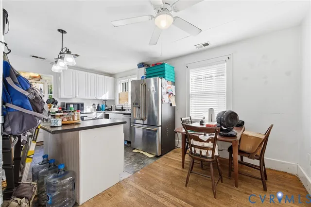 a kitchen with stainless steel appliances granite countertop a dining table chairs refrigerator and sink