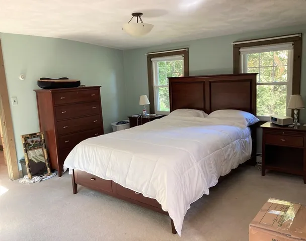 a bedroom with a bed and dresser with mirror