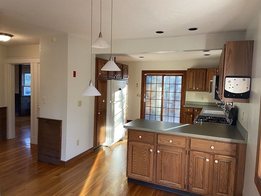 751 Central Avenue Needham, MA 02494 - Photo 5 of 21 a kitchen with stainless steel appliances granite countertop a refrigerator a sink dishwasher a stove and a dining table with wooden floor