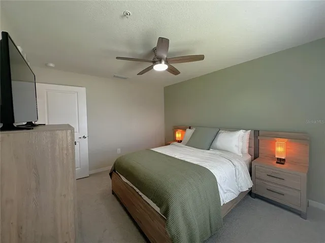 a bedroom with a bed and a flat tv screen on dresser