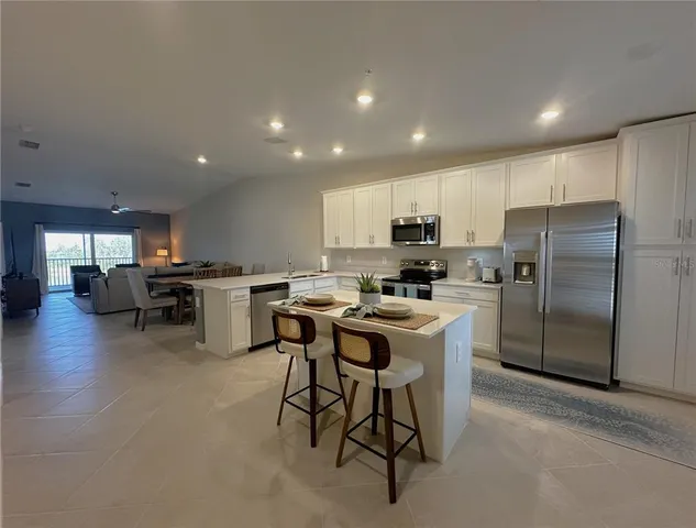 a kitchen with a refrigerator a counter top space cabinets and stainless steel appliances