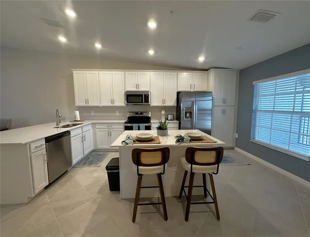 a kitchen with kitchen island white cabinets sink and stainless steel appliances