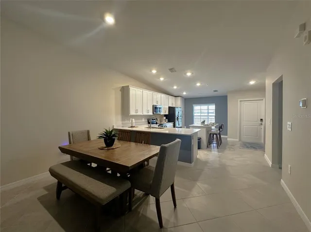 a kitchen with a dining table chairs and view of living room