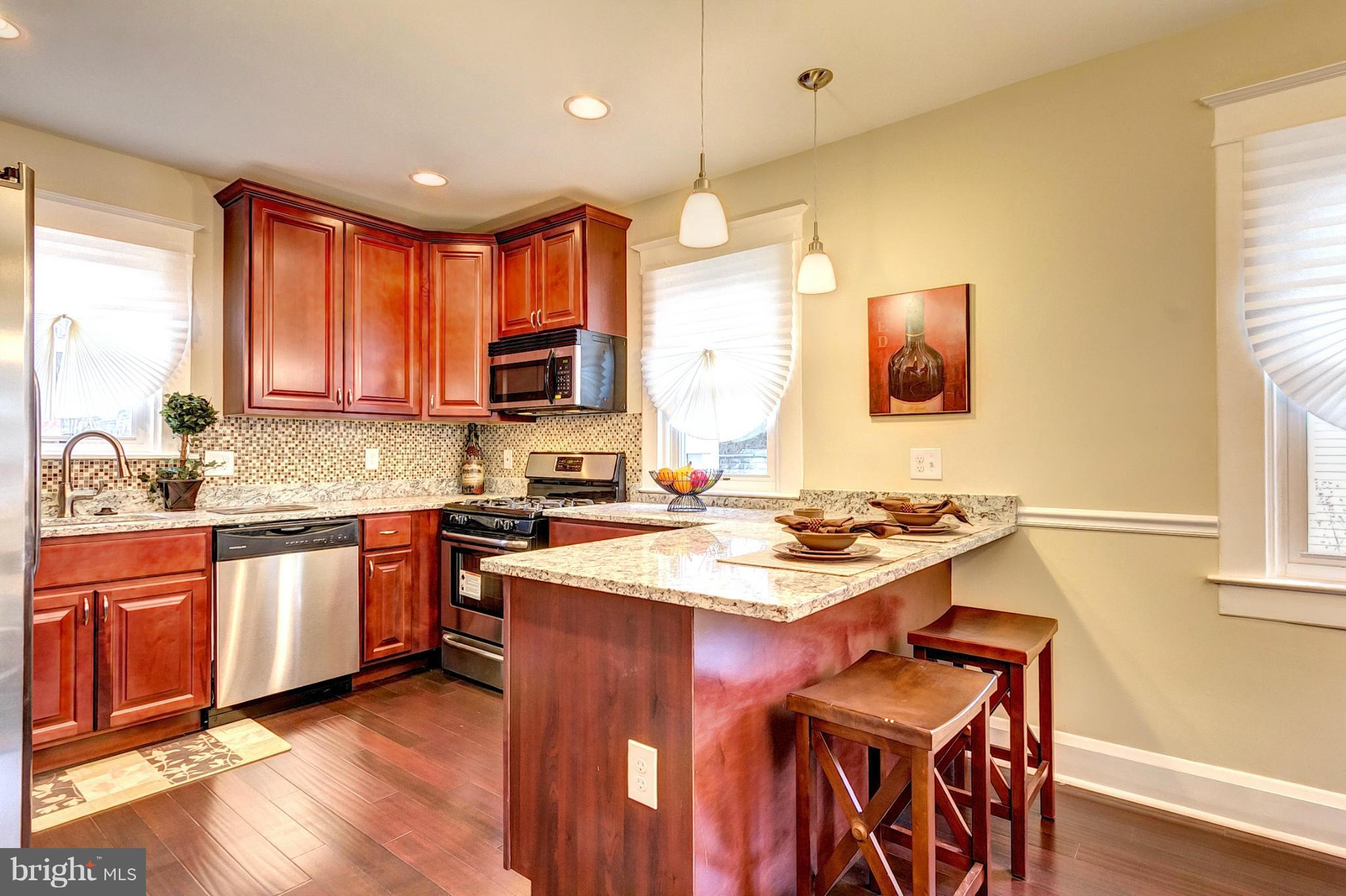 5800 Clearspring Road Baltimore, MD 21212 - Photo 8 of 30 a kitchen with stainless steel appliances granite countertop a stove a sink dishwasher a microwave oven and a dining table with wooden floor