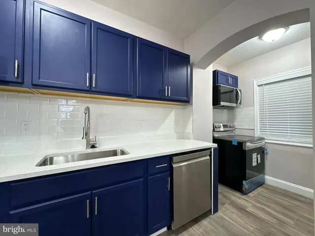 a kitchen with a sink and a stove top oven with wooden floor