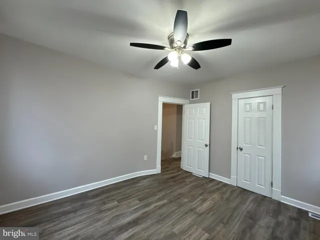 an empty room with wooden floor closet and windows