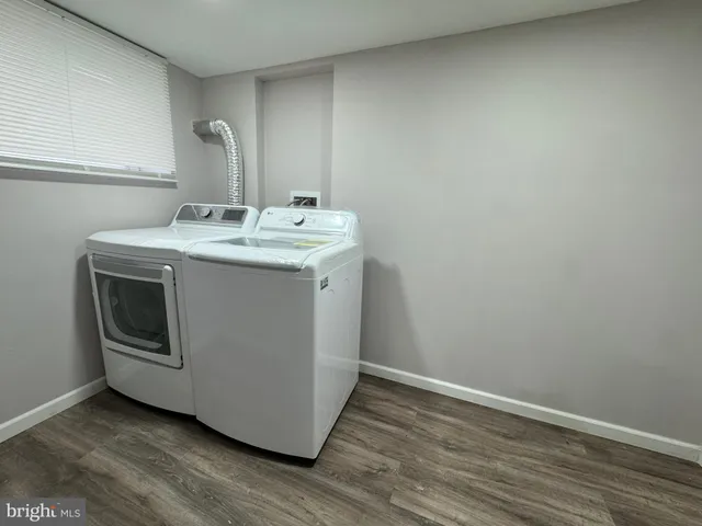 a utility room with wooden floor washer and dryer