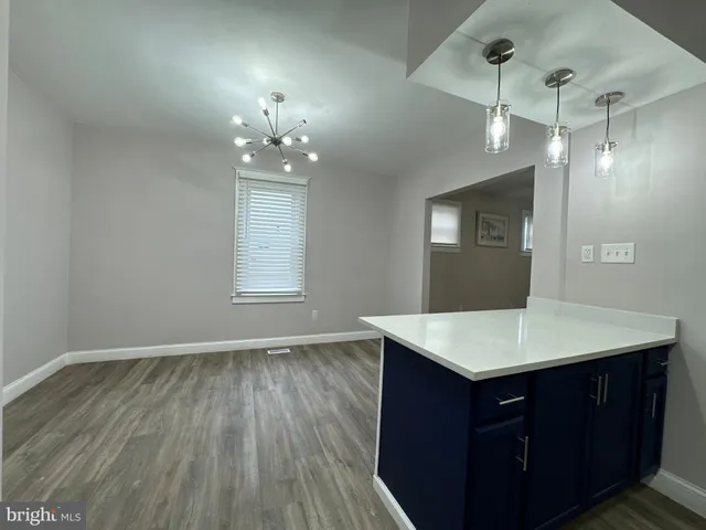 a room with a chandelier fan and wooden floor