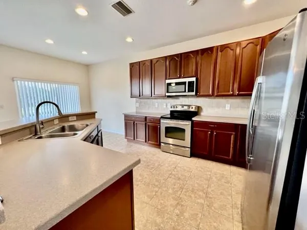 a view of an empty room with wooden floor and a ceiling fan