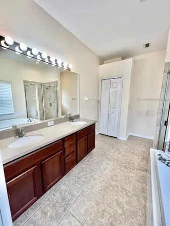 a bathroom with a double vanity sink toilet mirror and bathtub