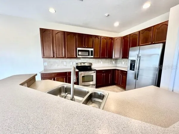 a kitchen with granite countertop wooden cabinets stainless steel appliances and a counter space