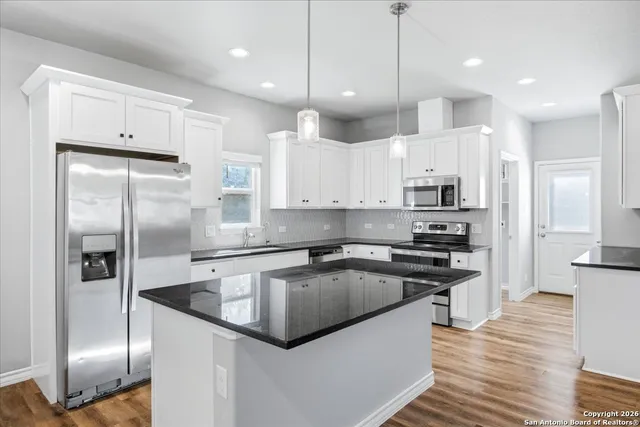 a kitchen with stainless steel appliances granite countertop a refrigerator a sink a stove and a refrigerator