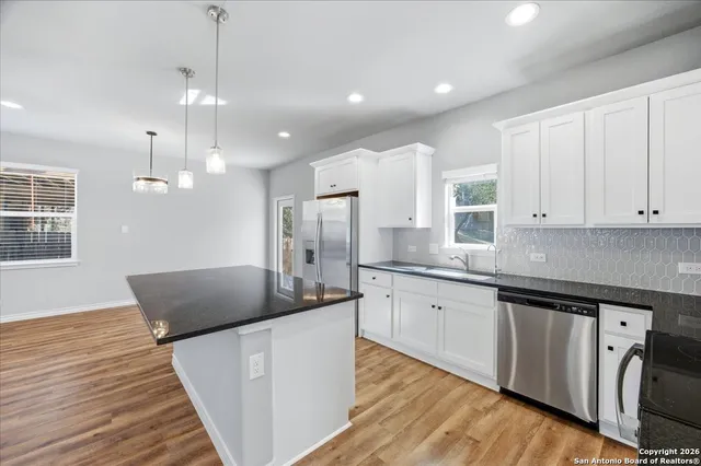 a large kitchen with granite countertop a white stove top oven a chimney wooden floor and cabinets