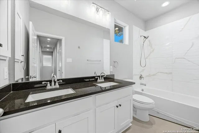 a bathroom with a granite countertop sink a toilet and a bathtub