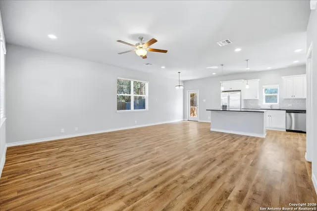 a view of an empty room with window and wooden floor