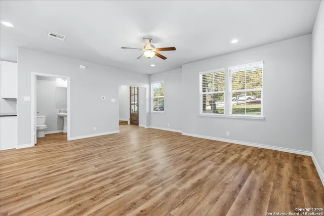 a view of an empty room with window and wooden floor