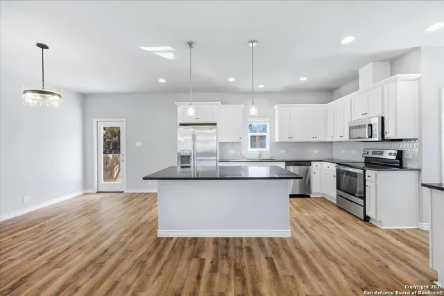 a large kitchen with granite countertop a large counter top a sink stainless steel appliances and cabinets