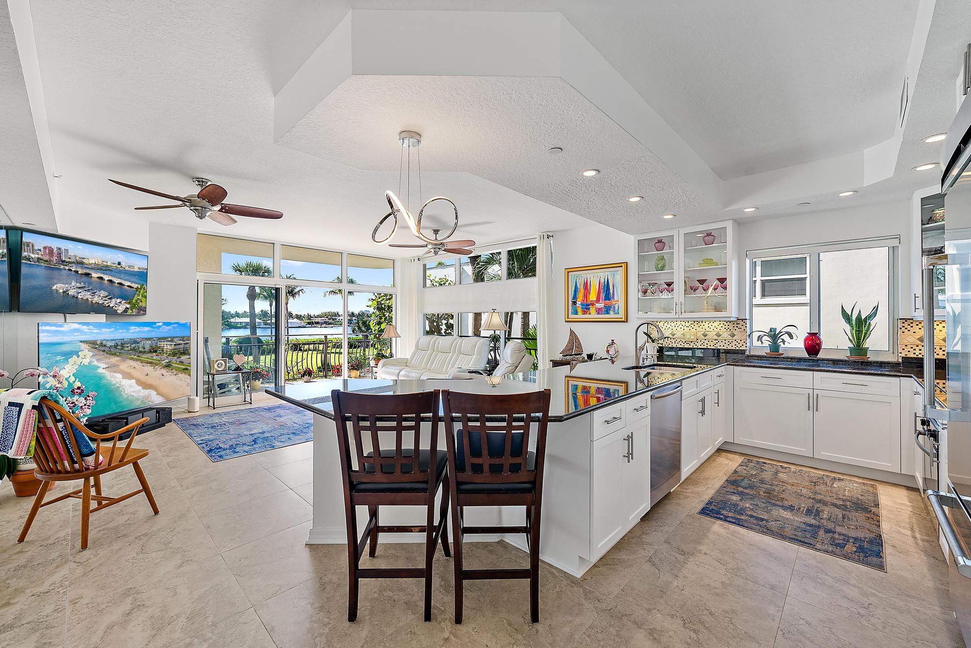 314 Inlet Way, Unit 103 Palm Beach Shores, FL 33404 - Photo 19 of 20 a kitchen with stainless steel appliances kitchen island granite countertop a table chairs sink and white cabinets