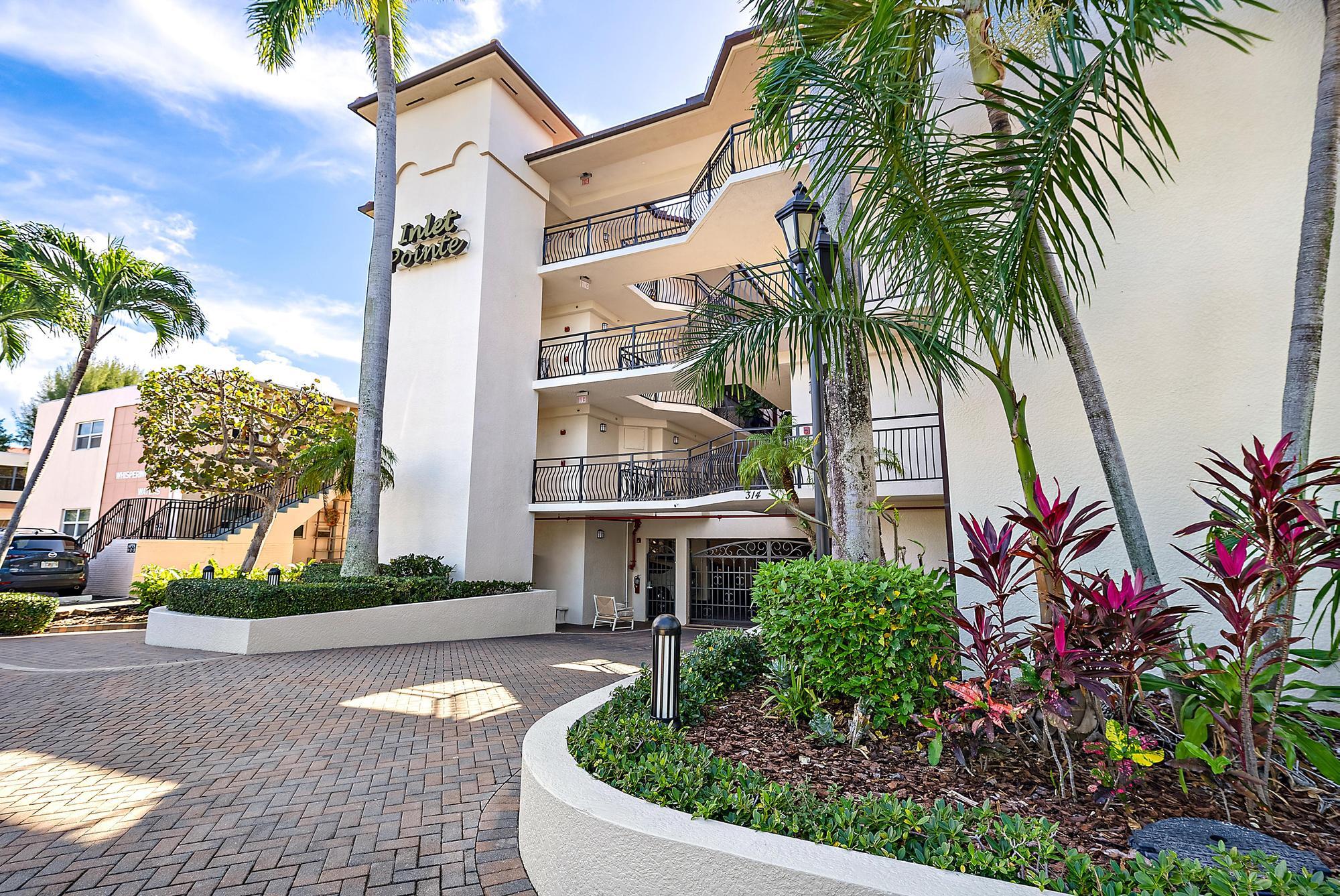 314 Inlet Way, Unit 103 Palm Beach Shores, FL 33404 - Photo 2 of 20 a front view of a house with a yard and potted plants